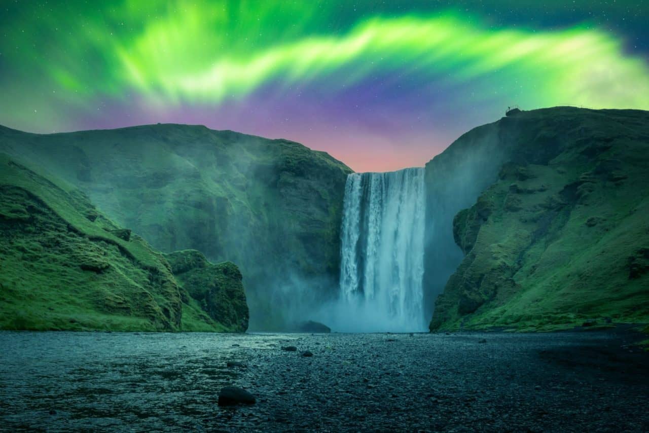 Skogafoss waterfall with green aurora