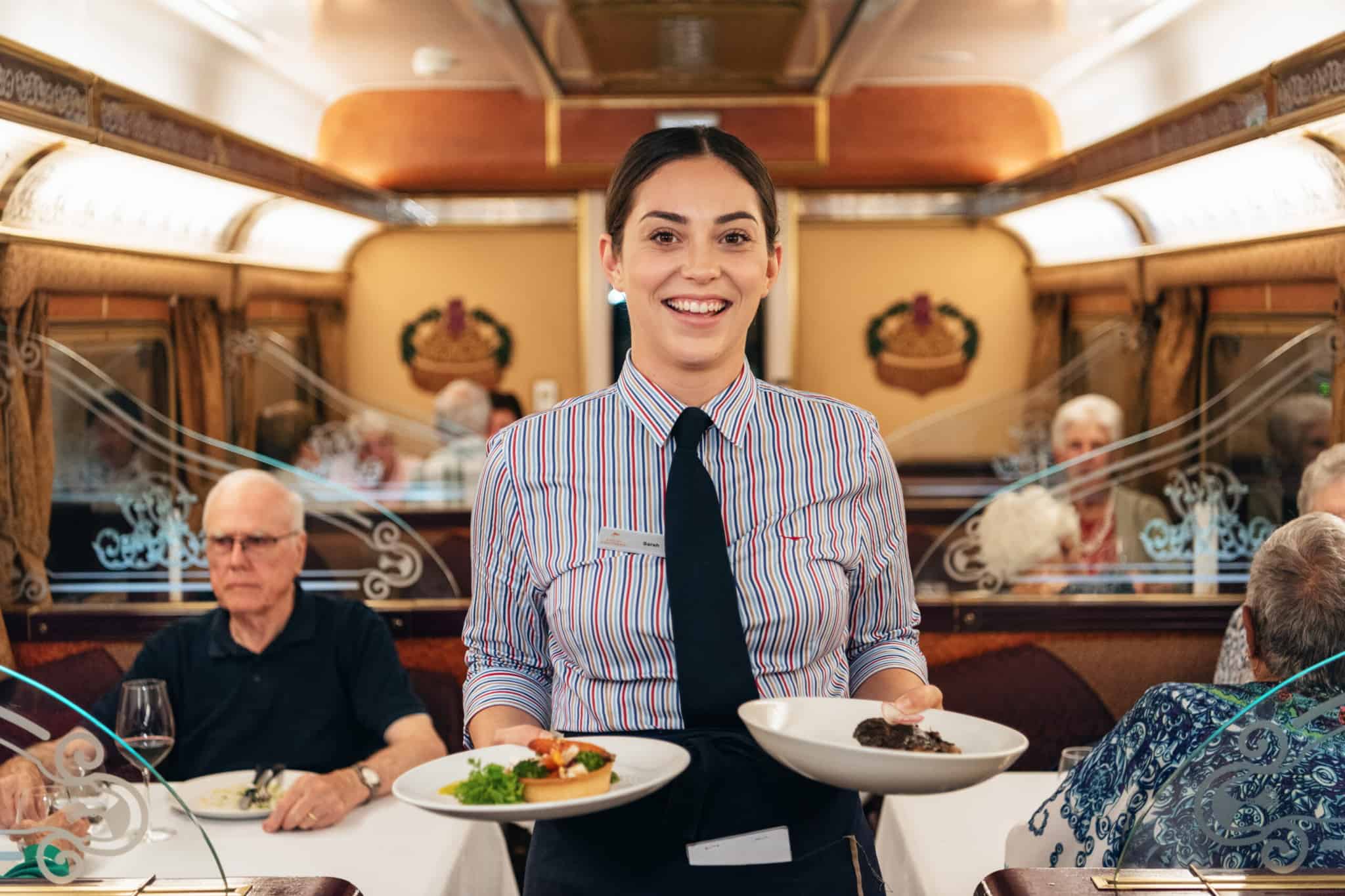 Waitress serving meals on The Ghan in restaurant car